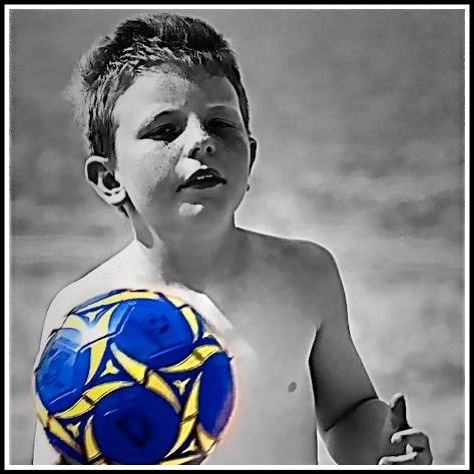 Alfie carrying his blue football while the rest of the photo is black and white
