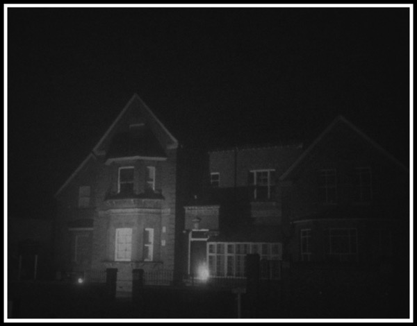 An old school building covered in fog illuminated in the darkness