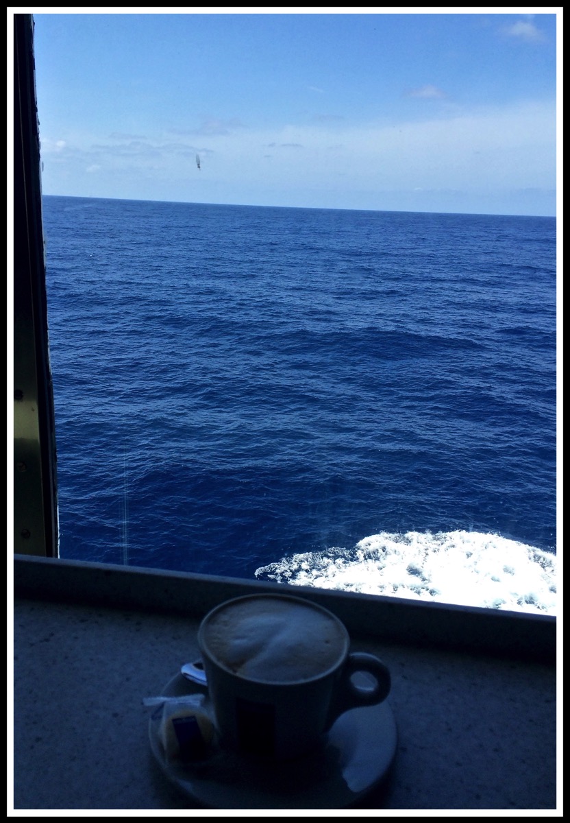 A Cappuccino on a window seat looking out over a beautiful blue seaat sea