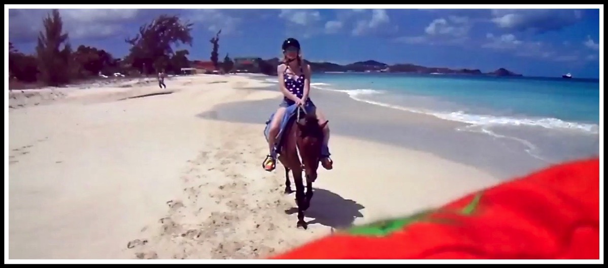 Photo of Sarah on her horse riding across stunning beach landscape with my orange shirt at the bottom as i took the photo over my shoulder