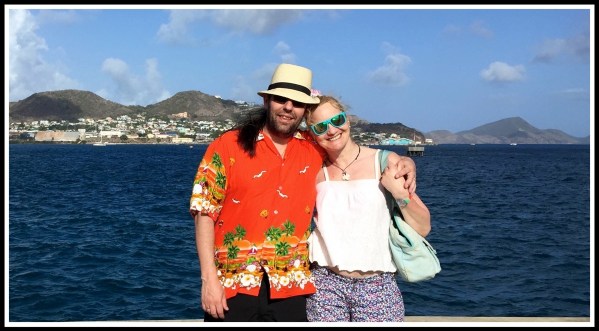 Me on the left in my bright orange shirt hugging Sarah on the right with the beautiful panorama of volcanic hills and blue sea behind us