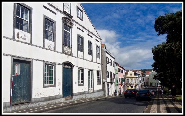 White buildings line the left of the pavement and road filling the whole image