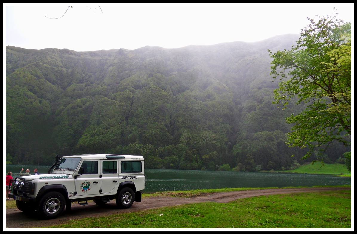 A 4x4 parked in front of a huge volcano and river