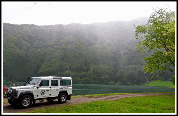 A 4x4 parked in front of a huge volcano and river