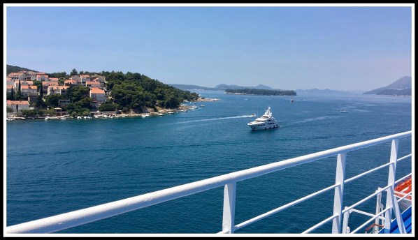 A view of the beautiful sea and houses along the bay with a small speed boat coming across the photo from right to left in Dubrovnik