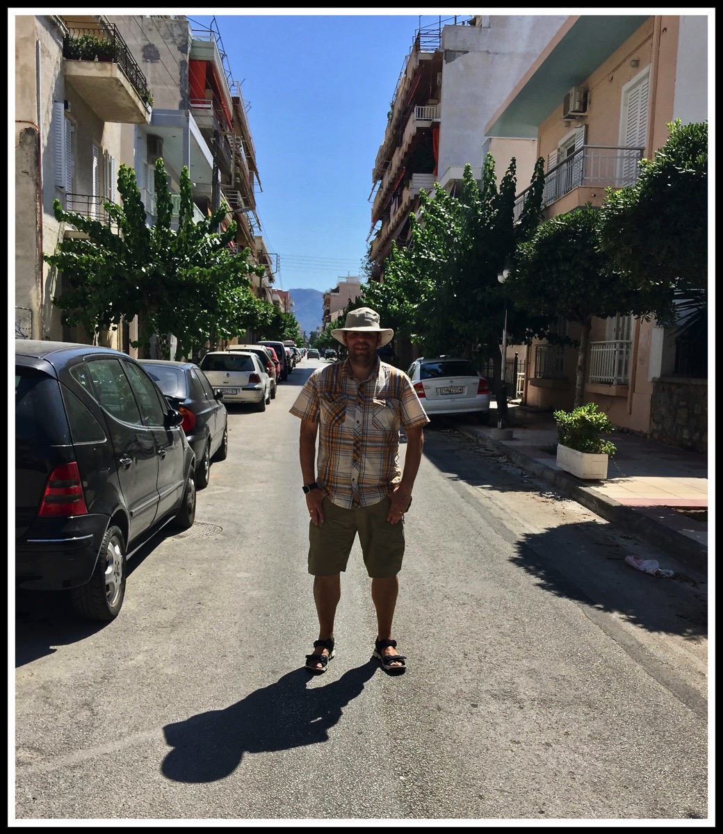 Me stood in the middle of the road with buildings either side in Corinth