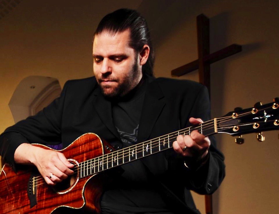 Me playing my Taylor K22ce at church and in front of a cross on the wall 