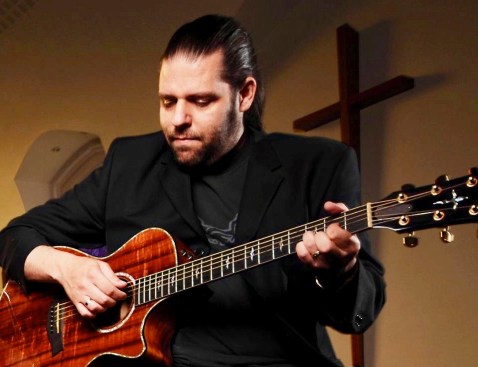 Me playing my Taylor K22ce at church and in front of a cross on the wall 