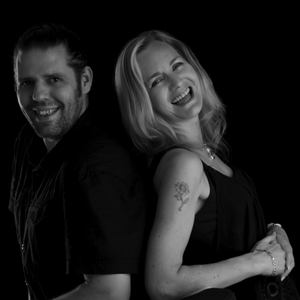 Black and white image of me and Sarah back to back and laughing our heads off