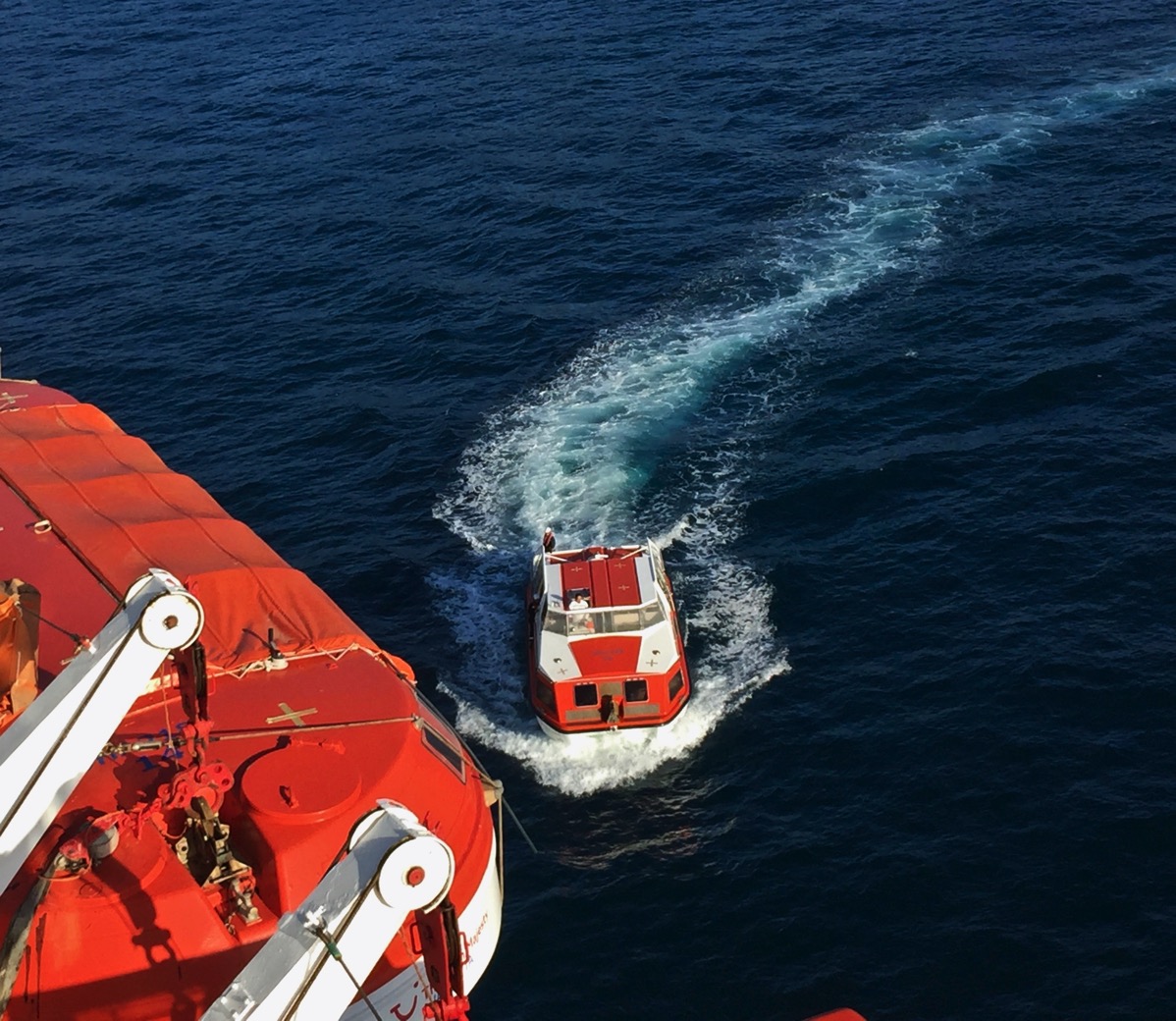 Close up of the little boat now pulled up alongside the ship whilst leaving lots of frothy waves behind
