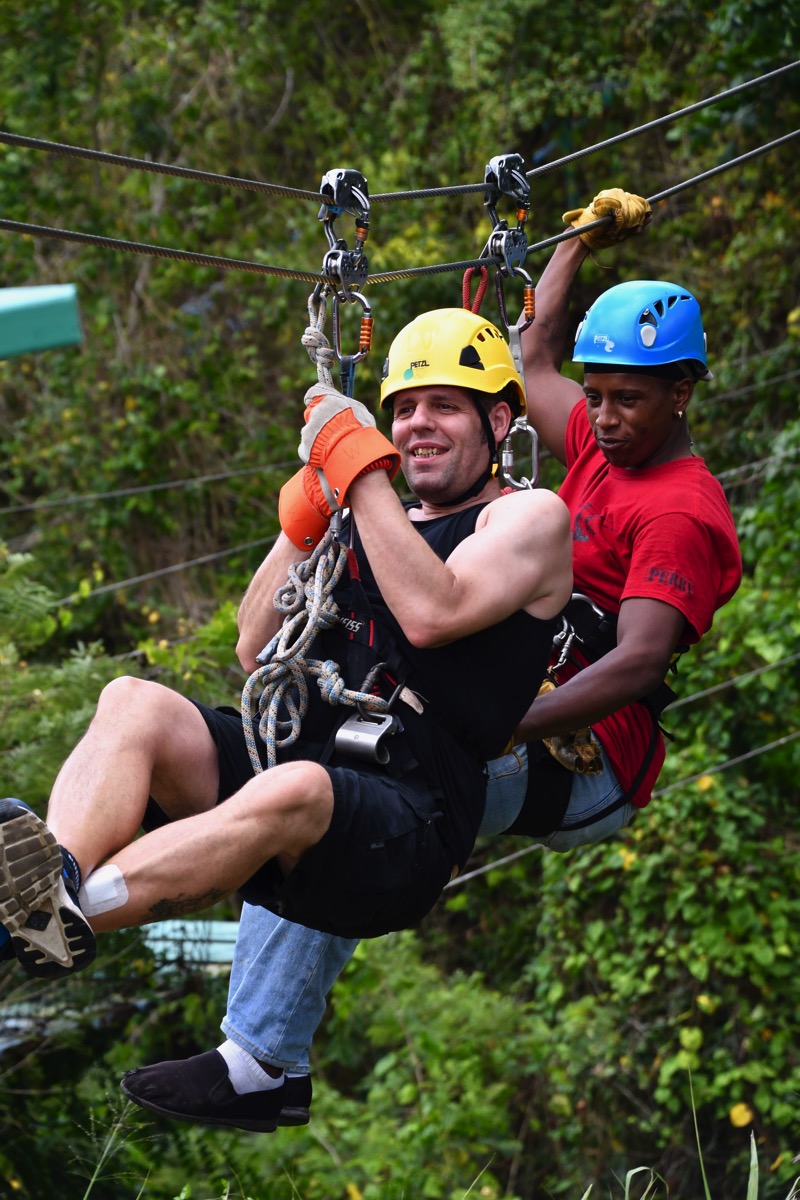 Me on the zip line with the zip line dude attached to me and we are high above the rain forest