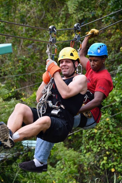 Me on the zip line with the zip line dude attached to me and we are high above the rain forest