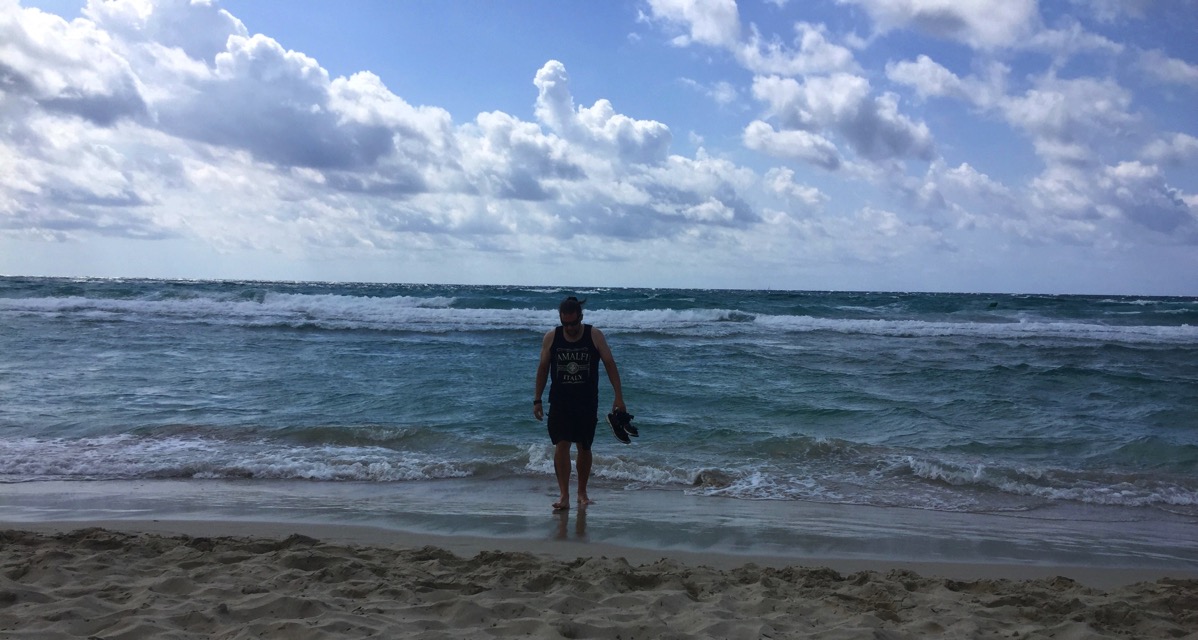 Me walking up from the sea after cooling my feet holding my sandals