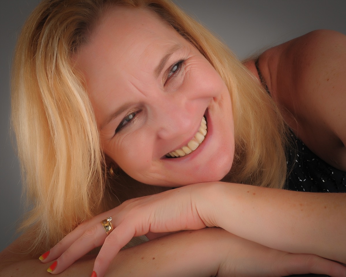 Sarah with head laying on her arms and a huge smile