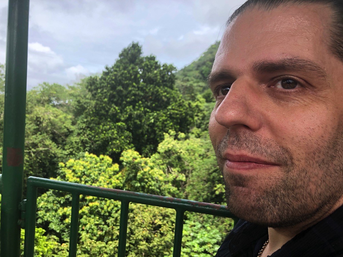 Very close up of me looking near the camera with the rain forest behind me