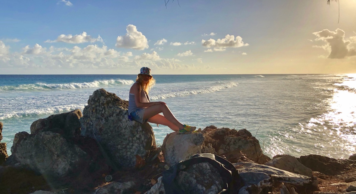 Sarah sat on the rocks in front of the beautiful Bajan sunset