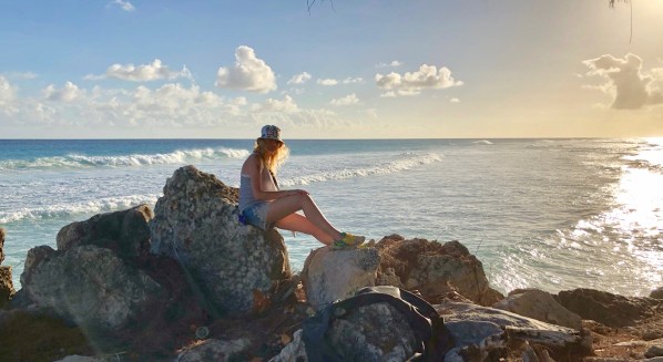 Sarah sat on the rocks in front of the beautiful Bajan sunset