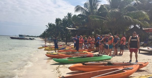 Me stood on the beach next to lots of kayaks with another group being shwed hwo to use them