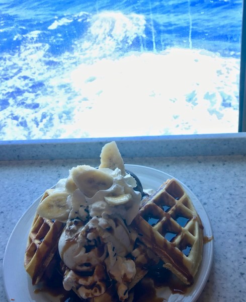 plate fo fresh fruit on a table top in front of a view outside across the ocean