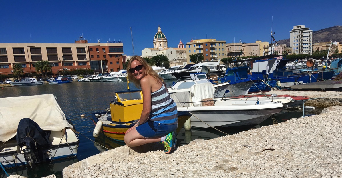 Sarah bent down and looking into one of the boats in a long row at the dock