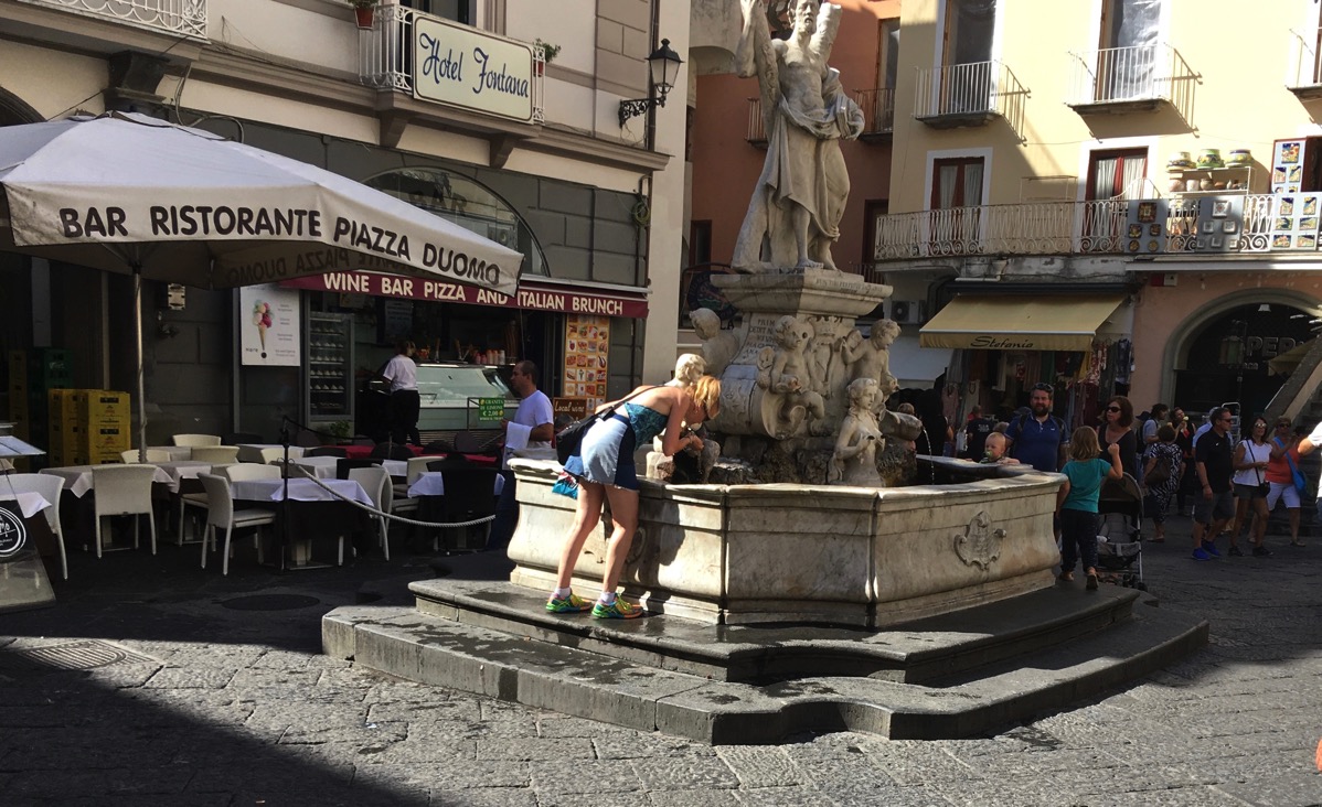 Sarah drinking from the natural water fountain in the Amalfi square