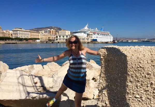 Sarah in a ruined wall with the ship in the background