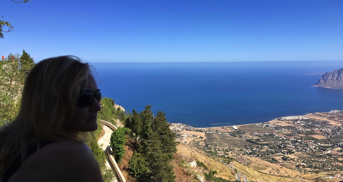 Sarah in shadow on the left looking out of the cable car to the sea below and the coastline of the right