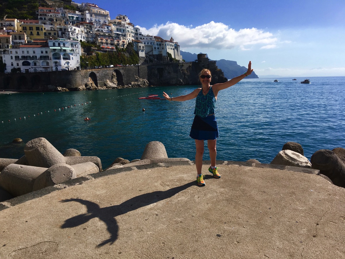 Sarah stood on the edge of the small dock with sea all around her and mountains in the background.jpg whilst showing her guns again in the bicepts pose