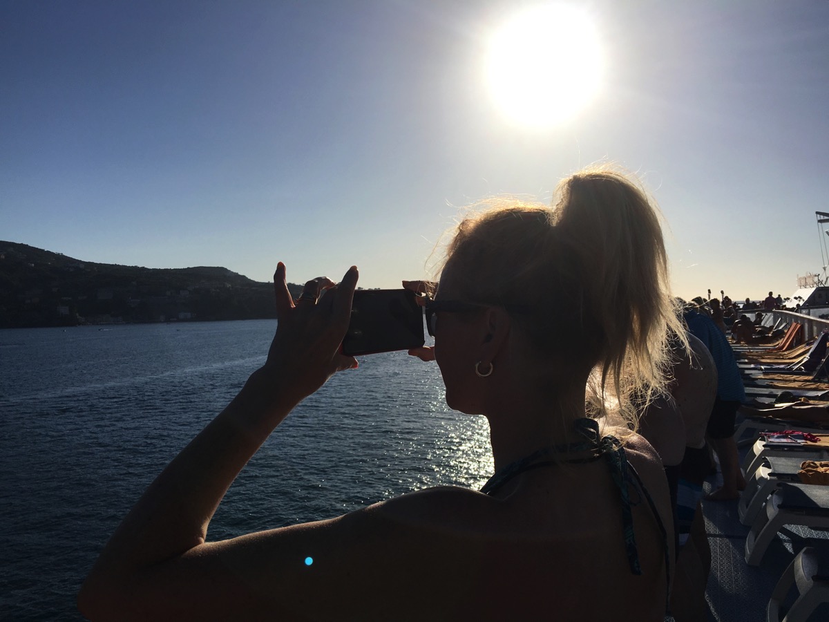 Sarah taking a photo of the sunset and landscape from the ship