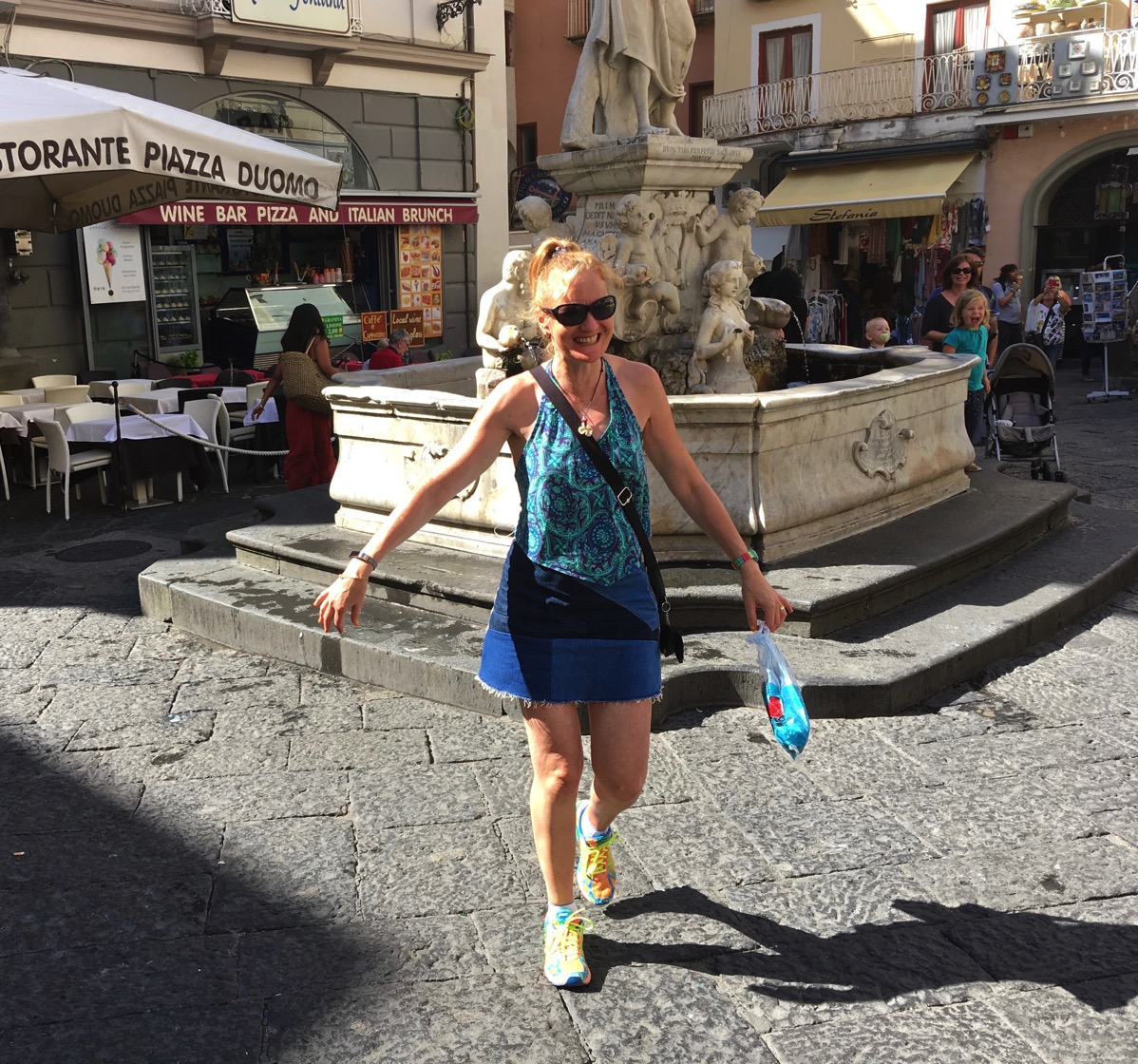Sarah walking away with wet hands after Sarah drinking from the natural water fountain in the Amalfi square