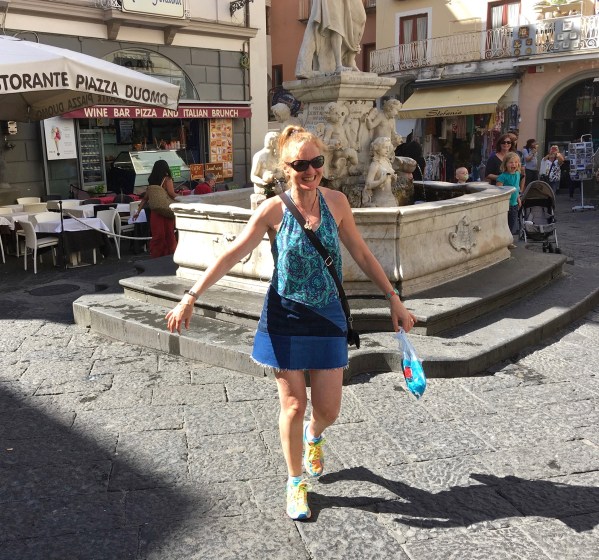 Sarah walking away with wet hands after Sarah drinking from the natural water fountain in the Amalfi square