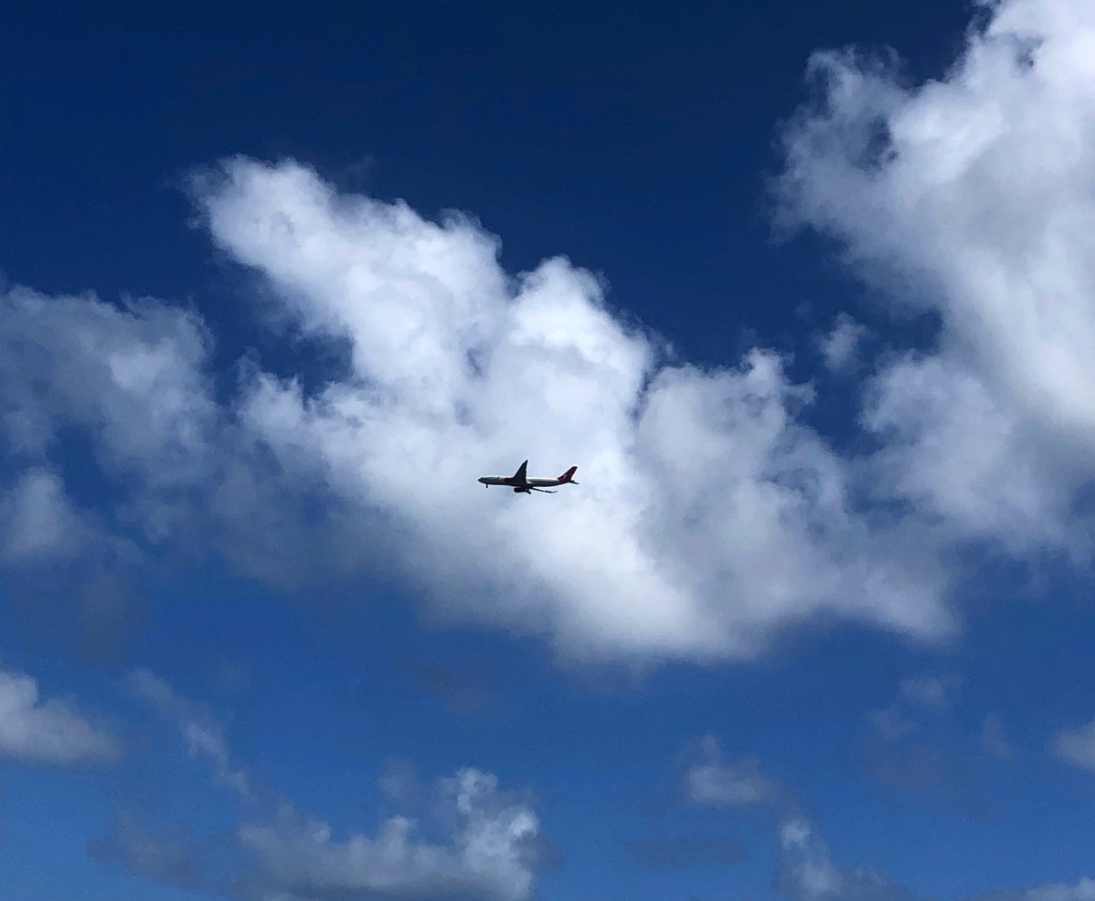 photo of a airplane flying through a fluffy white cloud in the blue sky