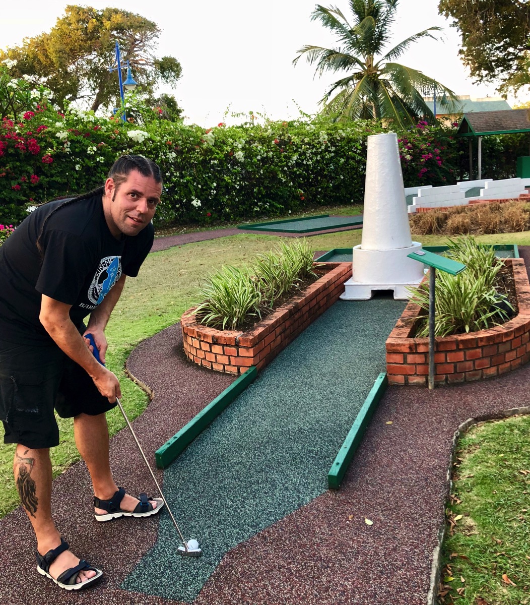 Me looking towards the camera whilst taking a shot on the lighthouse crazy golf course at southern palm Barbados