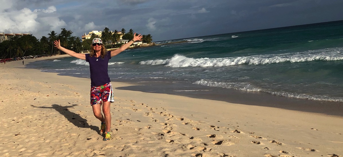 Sarah with arms in the air on Dover beah Barbados