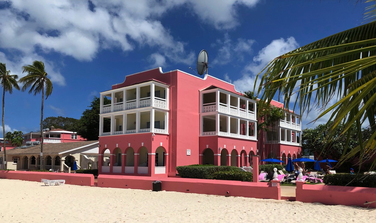 Photo of the pink hotel taken from the beach with palm trees around